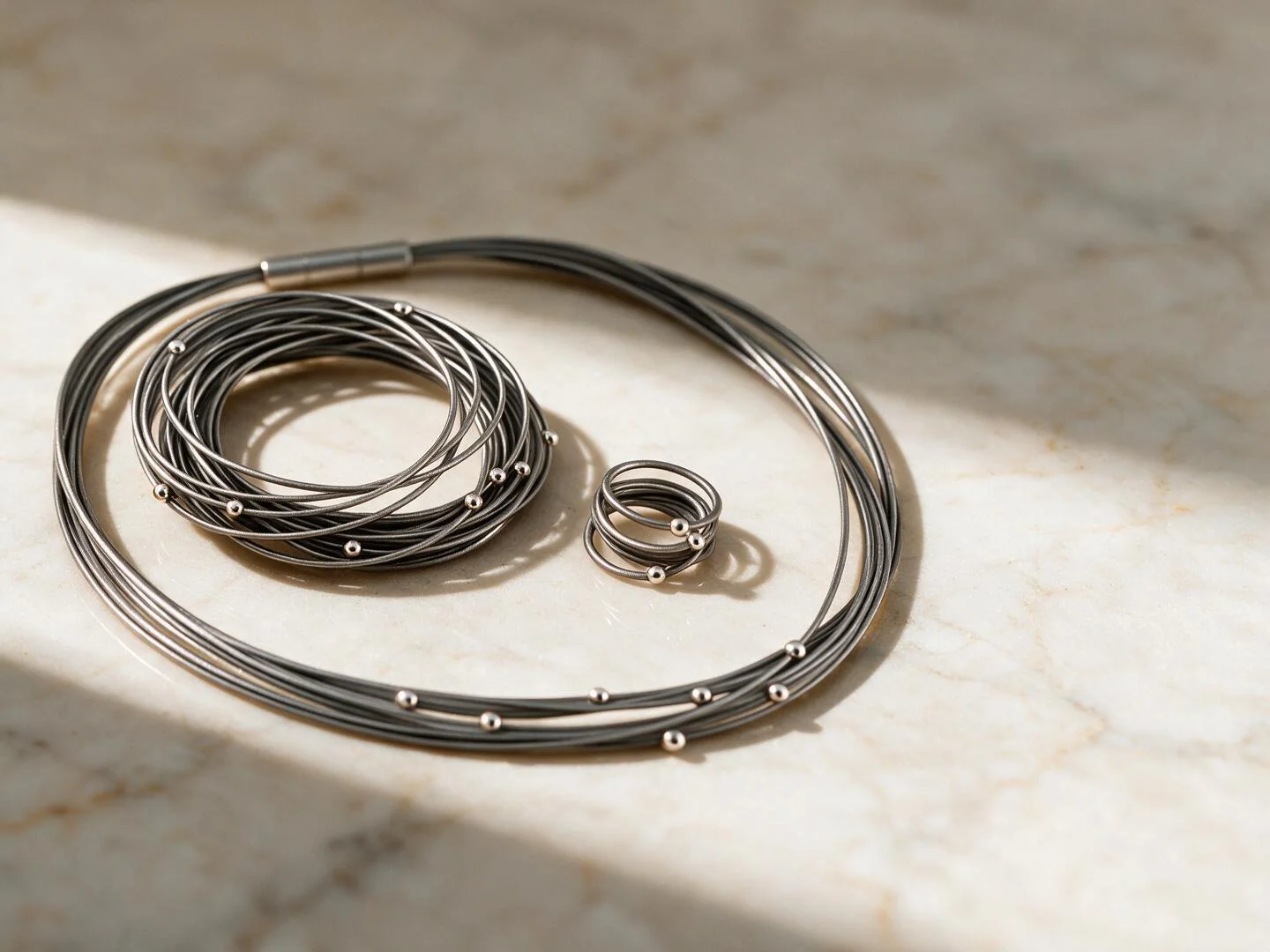 Colgante y anillo de acero y plata sobre mármol